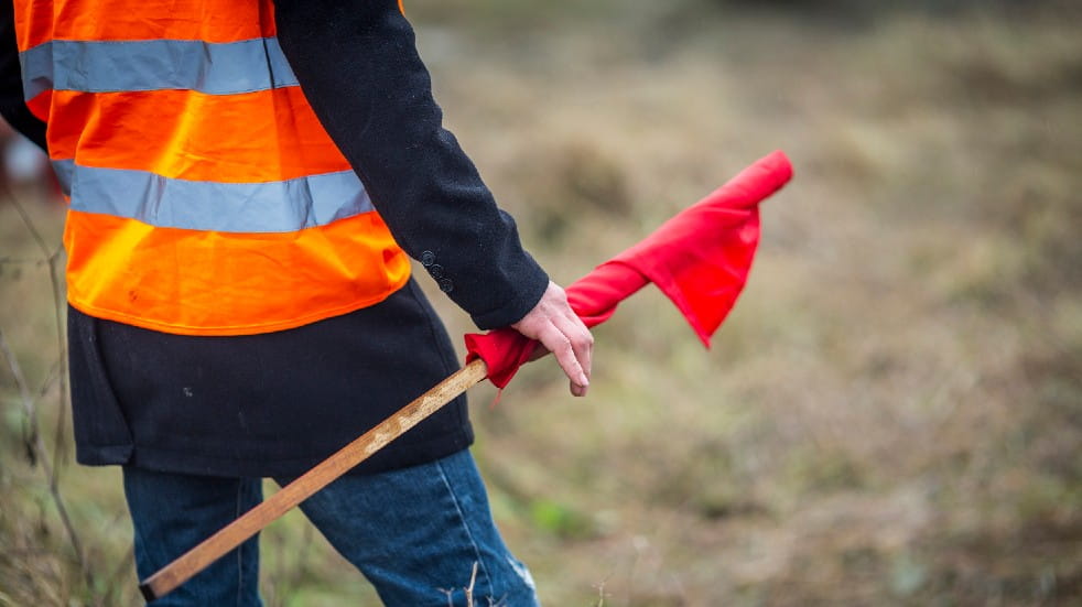Help your community recover from the pandemic marshal in high-vis jacket with flag